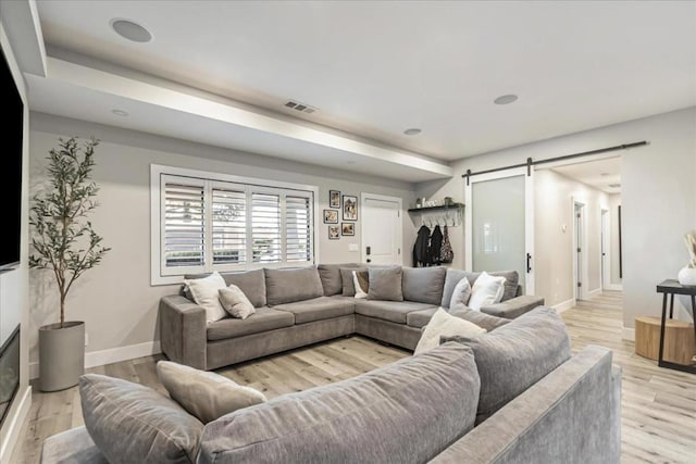 living room with a barn door and light hardwood / wood-style floors