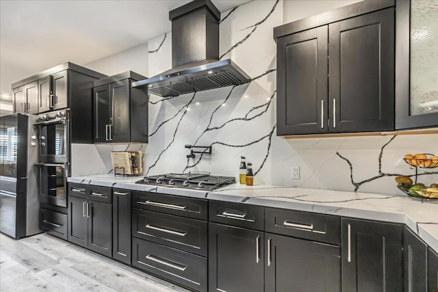 kitchen featuring stainless steel gas cooktop, decorative backsplash, island exhaust hood, and light hardwood / wood-style flooring