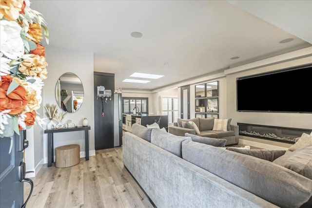 living room with light hardwood / wood-style flooring and a skylight