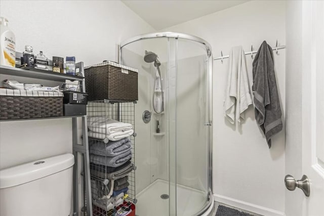 bathroom featuring toilet and a shower with door