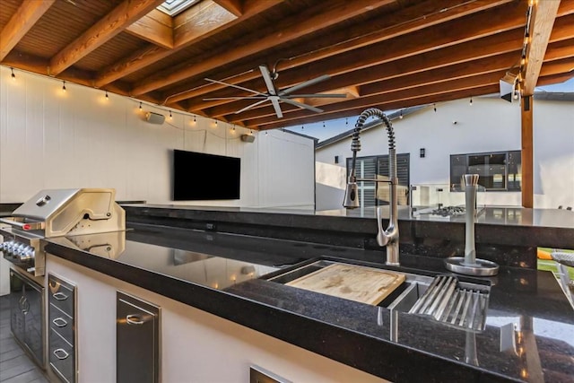 kitchen featuring a skylight, track lighting, and dark stone counters