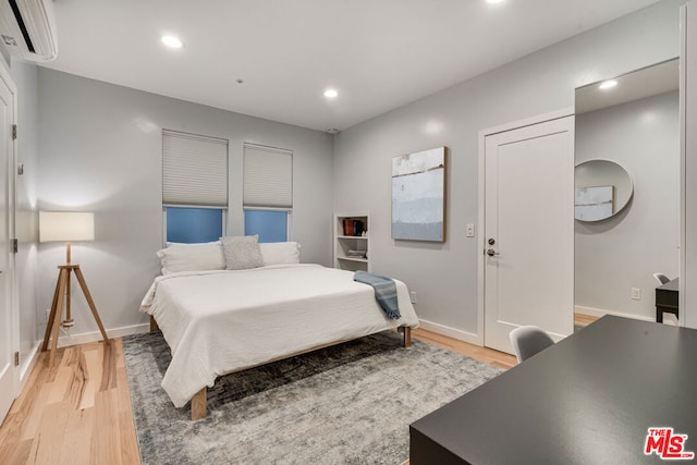 bedroom featuring light hardwood / wood-style floors and a wall unit AC