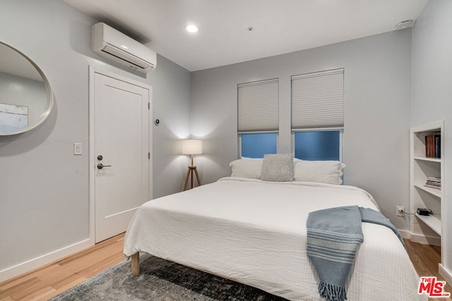 bedroom with hardwood / wood-style floors and a wall mounted air conditioner