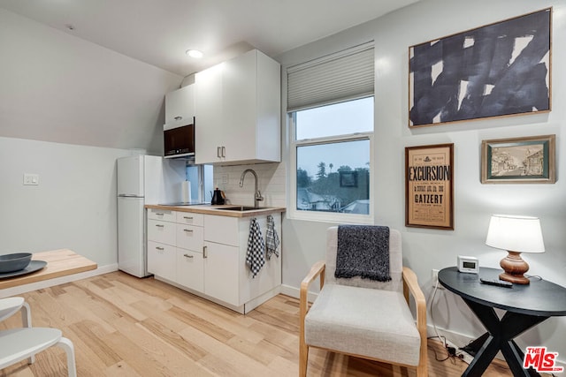 kitchen featuring sink, white cabinets, tasteful backsplash, and light wood-type flooring