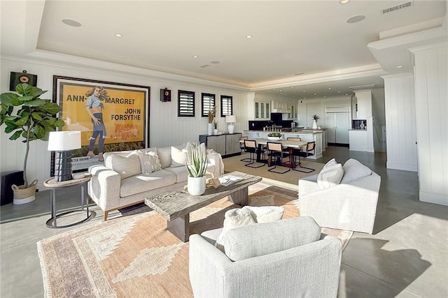 living room featuring concrete floors, a tray ceiling, and ornamental molding