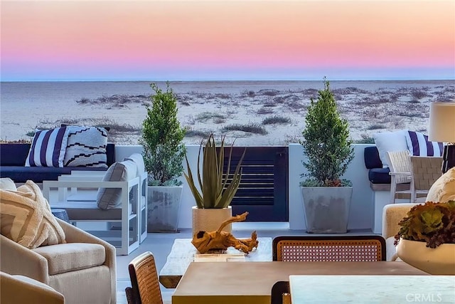 snow covered back of property featuring a water view, a patio, and an outdoor hangout area