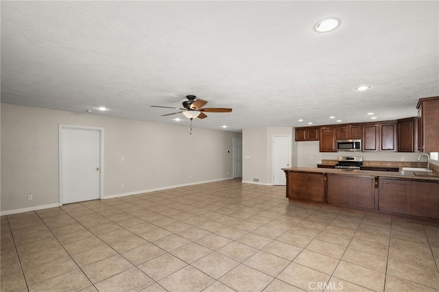 kitchen featuring ceiling fan, sink, kitchen peninsula, a textured ceiling, and appliances with stainless steel finishes