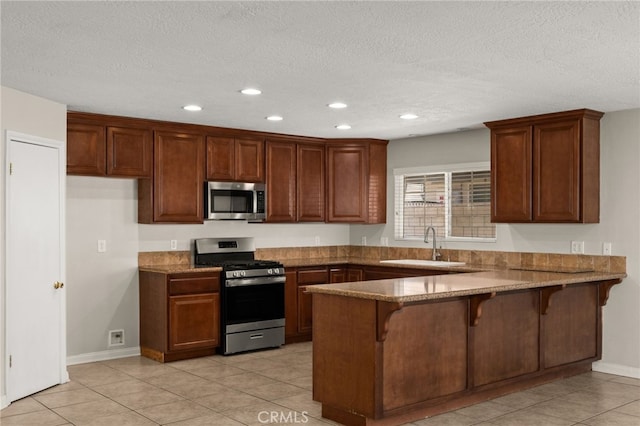 kitchen featuring sink, stainless steel appliances, kitchen peninsula, a breakfast bar area, and light tile patterned floors