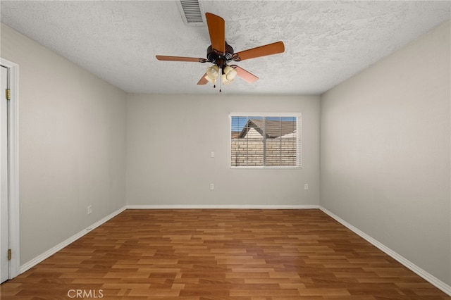 empty room with ceiling fan, wood-type flooring, and a textured ceiling