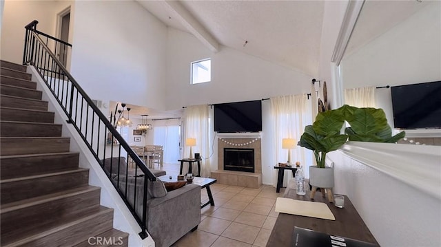 living room with beamed ceiling, light tile patterned floors, high vaulted ceiling, and a tiled fireplace