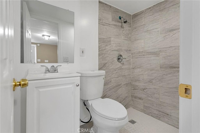 bathroom featuring toilet, vanity, and tiled shower