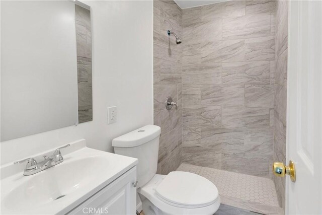 bathroom featuring vanity, toilet, and tiled shower