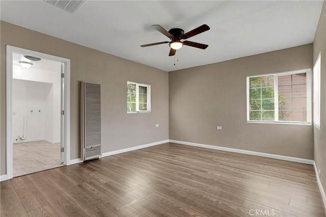 unfurnished bedroom with ceiling fan, multiple windows, and hardwood / wood-style floors