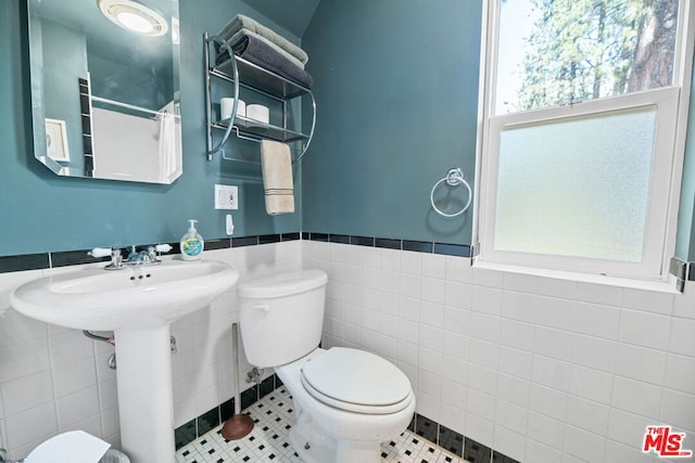 bathroom with tile patterned flooring, toilet, and tile walls