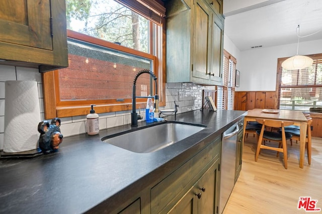 kitchen featuring sink, stainless steel dishwasher, tasteful backsplash, decorative light fixtures, and light hardwood / wood-style floors