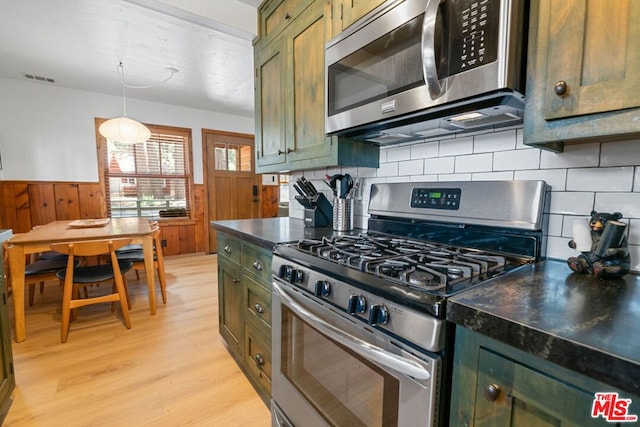 kitchen featuring appliances with stainless steel finishes, backsplash, decorative light fixtures, light hardwood / wood-style flooring, and green cabinets