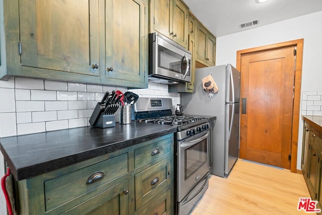 kitchen with tasteful backsplash, stainless steel appliances, and light hardwood / wood-style flooring