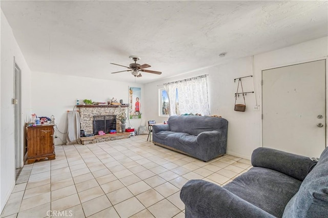 tiled living room featuring a stone fireplace and ceiling fan