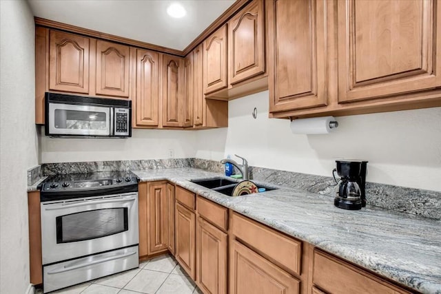 kitchen with light stone counters, sink, light tile patterned floors, and stainless steel appliances