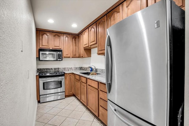 kitchen with light stone countertops, light tile patterned floors, sink, and appliances with stainless steel finishes