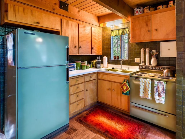 kitchen with fridge, beam ceiling, sink, and electric range