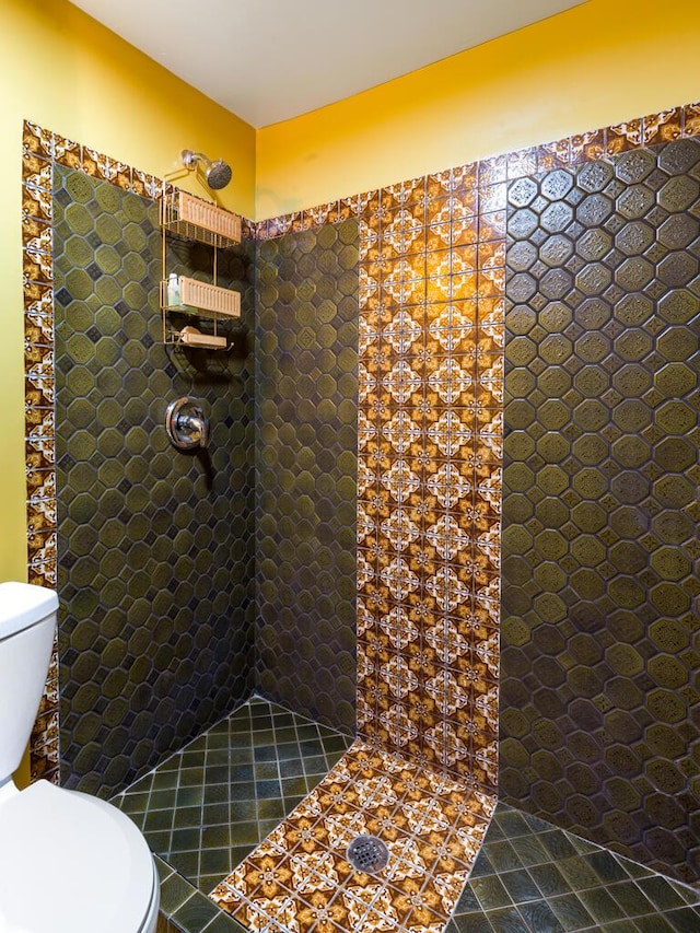 bathroom with tiled shower, toilet, and tile patterned flooring