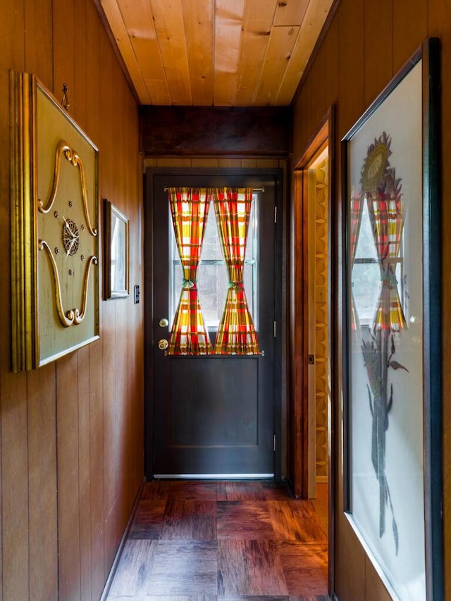 doorway to outside featuring wood ceiling and wooden walls