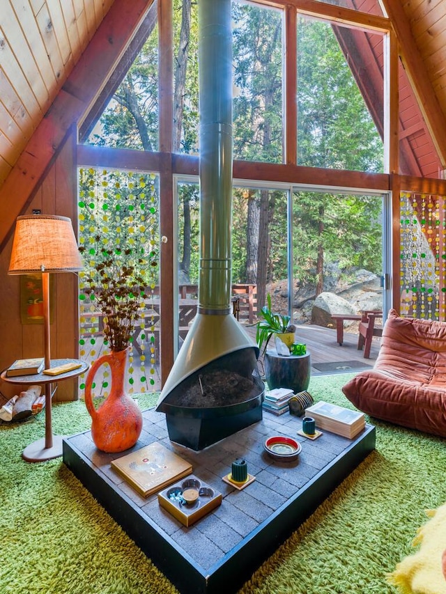 carpeted living room with beamed ceiling, a healthy amount of sunlight, a wood stove, and wood ceiling