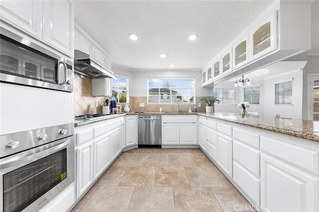 kitchen with crown molding, light stone countertops, tasteful backsplash, white cabinetry, and stainless steel appliances