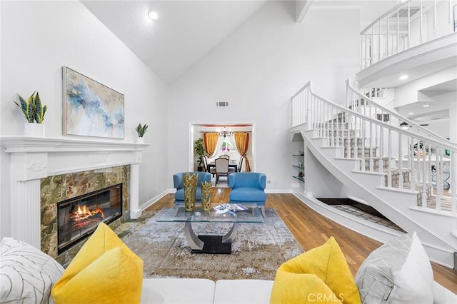 living room with hardwood / wood-style flooring, high vaulted ceiling, and a tiled fireplace