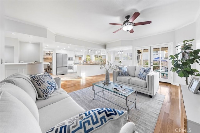 living room with french doors, light wood-type flooring, ceiling fan, and ornamental molding