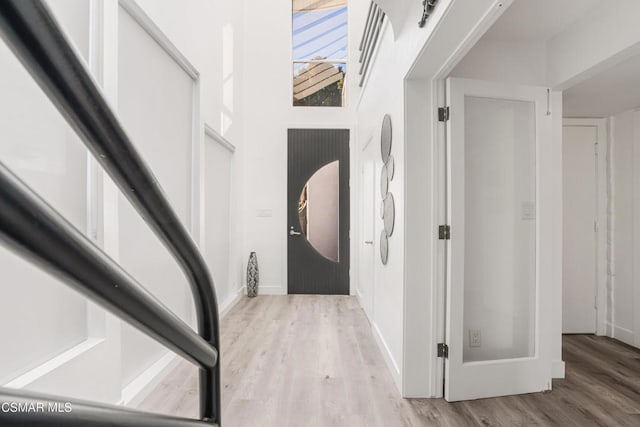 foyer entrance featuring a towering ceiling and light hardwood / wood-style floors