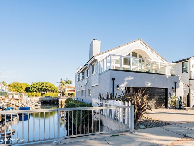 exterior space with a balcony, a garage, and a water view