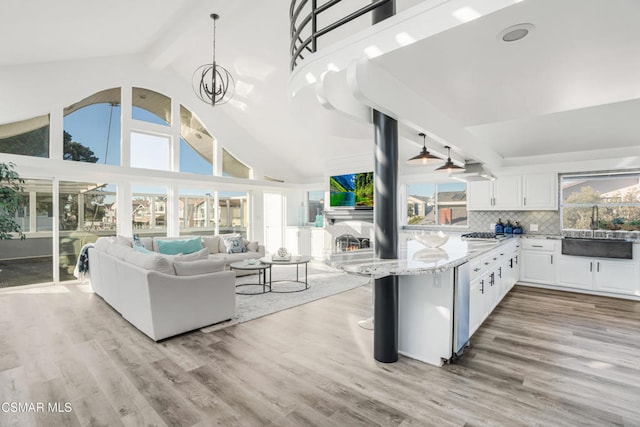 kitchen with white cabinetry, sink, pendant lighting, and light hardwood / wood-style floors