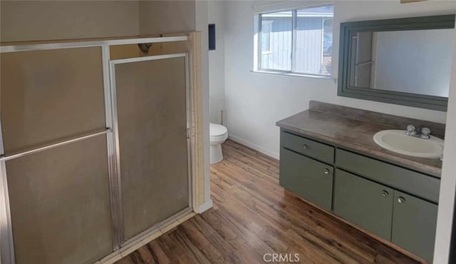 bathroom featuring vanity, hardwood / wood-style flooring, toilet, and a shower with shower door