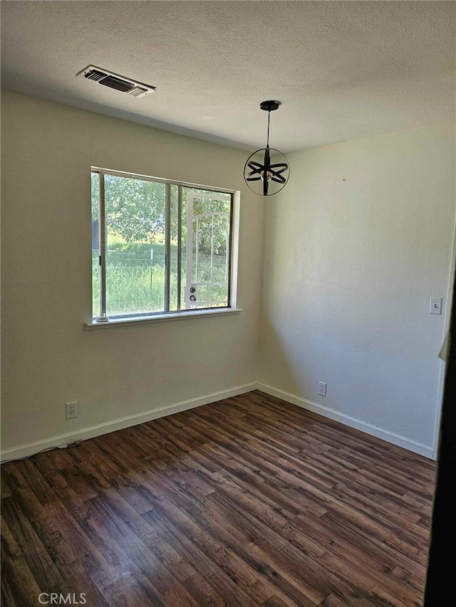 unfurnished room featuring a chandelier, a textured ceiling, and dark hardwood / wood-style floors