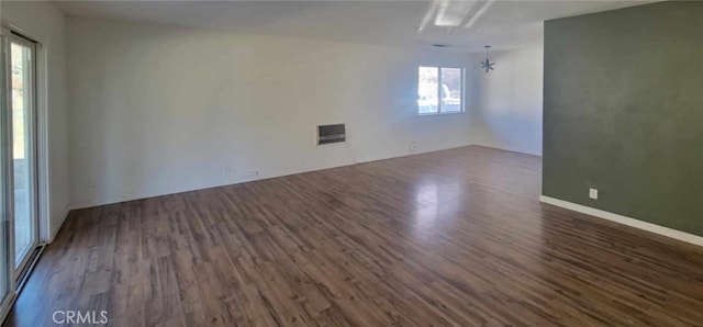 unfurnished room with dark wood-type flooring, a healthy amount of sunlight, and an inviting chandelier