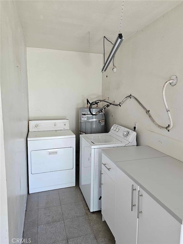 clothes washing area featuring cabinets, strapped water heater, and washing machine and dryer