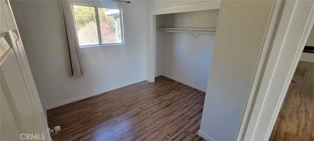 unfurnished bedroom featuring a closet and dark wood-type flooring