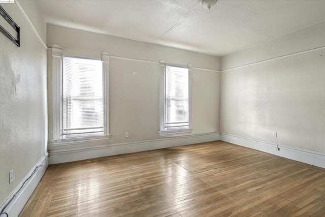 unfurnished room featuring plenty of natural light and hardwood / wood-style flooring