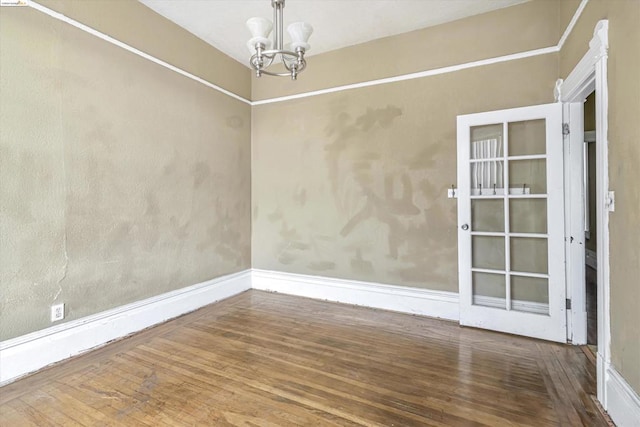 spare room with wood-type flooring and a notable chandelier