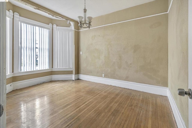 empty room featuring hardwood / wood-style floors and a notable chandelier