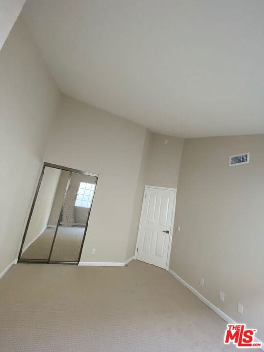 unfurnished bedroom with light colored carpet and a closet