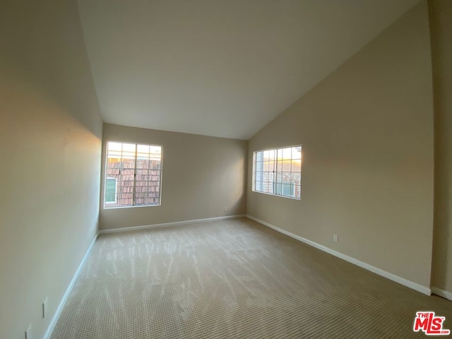 carpeted empty room with a healthy amount of sunlight and vaulted ceiling