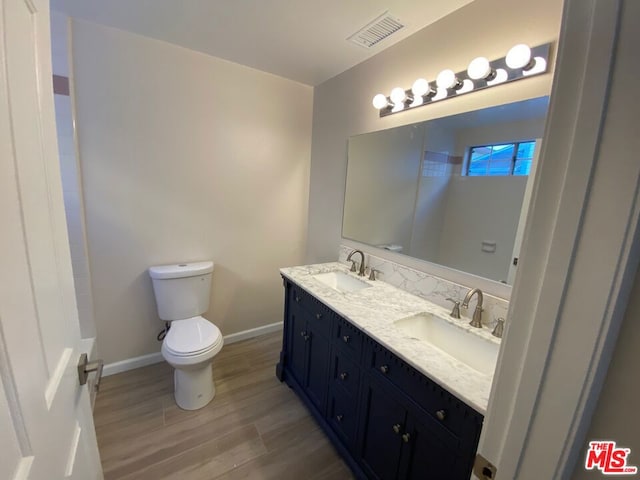 bathroom featuring toilet, wood-type flooring, and vanity