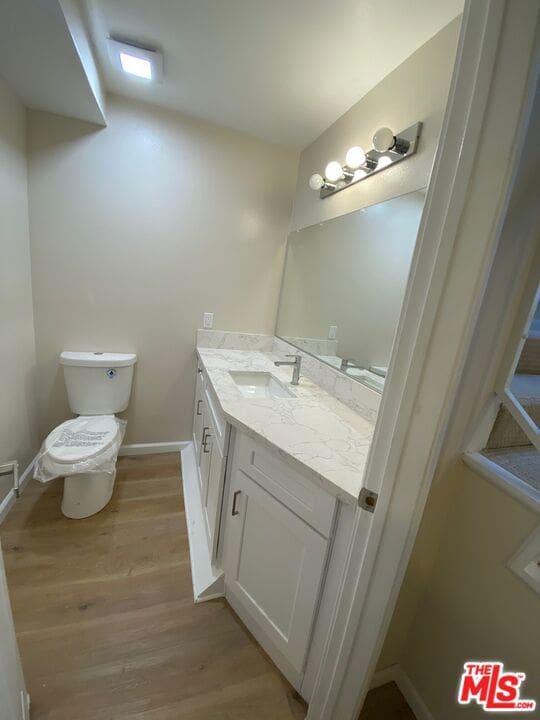 bathroom featuring toilet, hardwood / wood-style flooring, and vanity