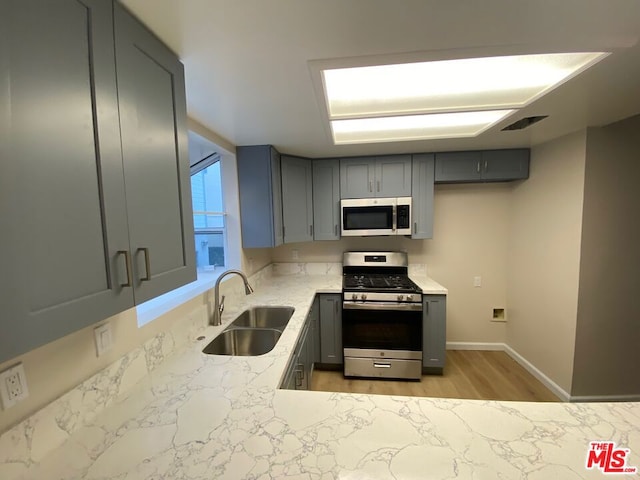 kitchen featuring appliances with stainless steel finishes, gray cabinets, and sink