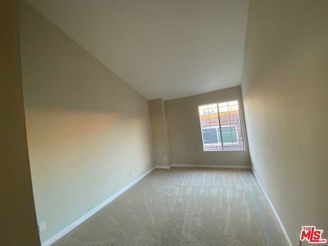 carpeted empty room featuring vaulted ceiling