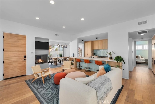 living room with a healthy amount of sunlight, sink, and light wood-type flooring