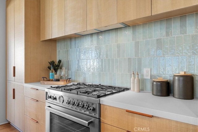 kitchen featuring light brown cabinets, backsplash, and high end stove